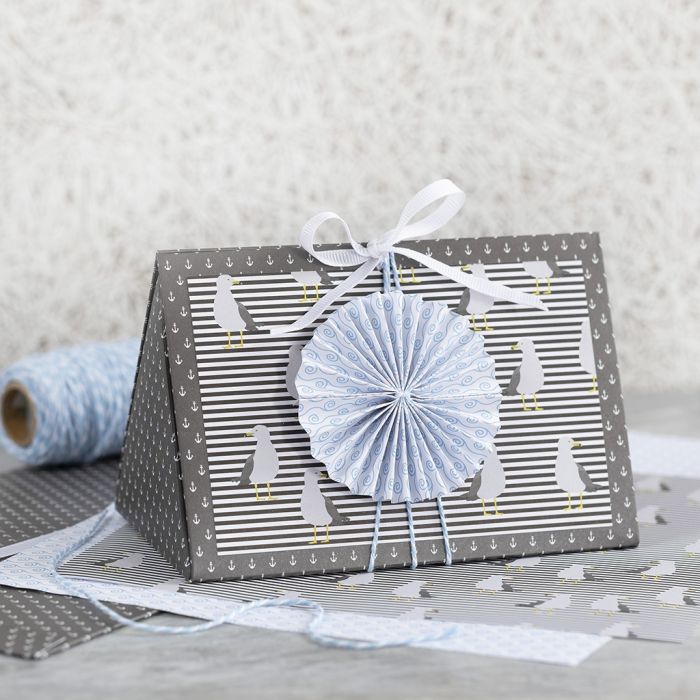 Geschenkverpackung in dunkelblau, verziert mit Rosette und Designpapier