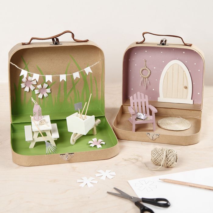 Kleine Koffer, die mit Farbe, Miniaturmöbeln und Accessoires in eine Gartenwelt verwandelt werden