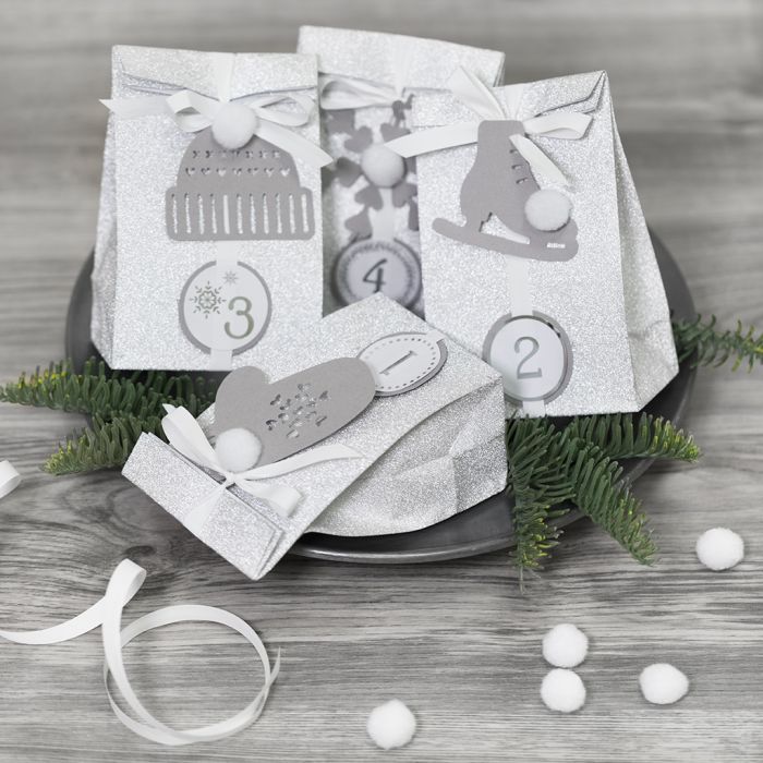Adventkalender-Geschenke, verziert mit Wintermotiven aus Karton und Pompons