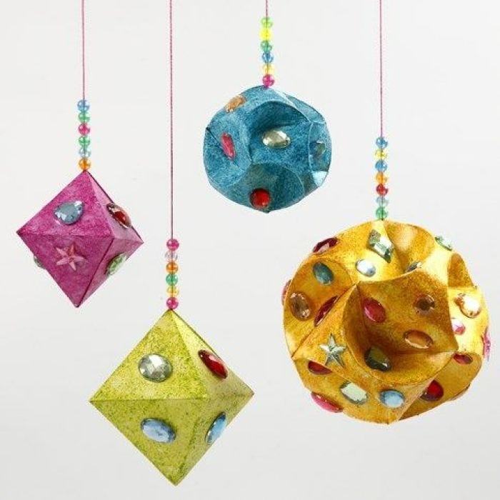 Hängedeko aus mit Strasssteinen und Glitzer verzierten Prismen und Kugeln aus Papier.