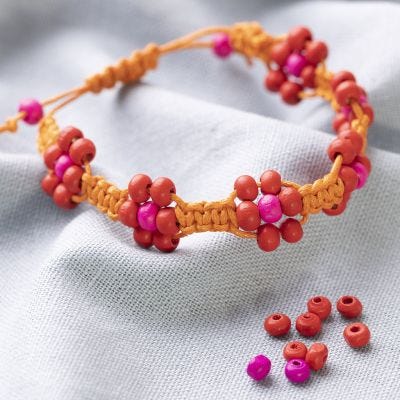 Ein geflochtenes Armband aus Baumwolle mit Perlen als große Blumen