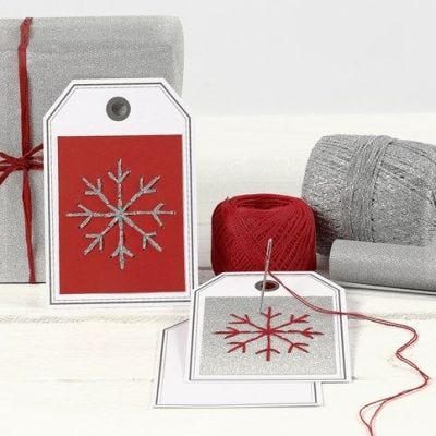 Eine Postkarte mit gestickter Schneeflocke als Geschenkanhänger