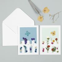 Grußkarte, verziert mit Trockenblumen und Zaun