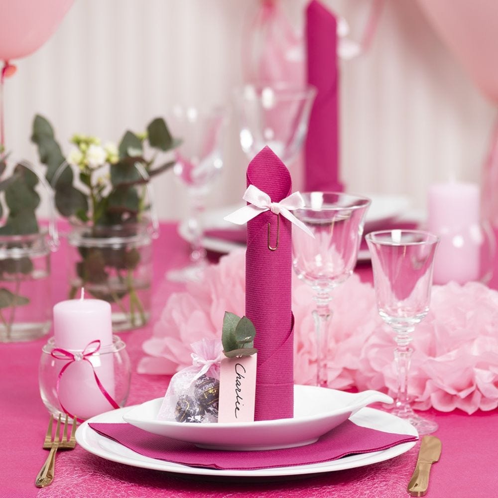 Tischdeko in Pink mit Papierblumen, Luftballons, zum Turm gefaltete Serviette und Platzkarten